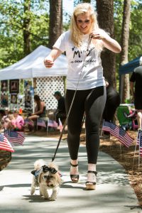 Snellville, GA, USA - May 14, 2016: A young woman proudly walks her dog in a dog fashion show at Pawfest, a dog festival on May 14, 2016 in Snellville, GA.